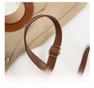Detail of adjustable brown leather shoulder strap with high-quality metal buckle and stitching