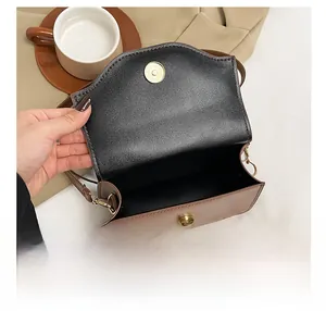 Detail view of the brown leather crossbody bag showing the magnetic snap and interior