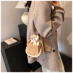 Detail of floral embossed beige box bag with pearl handle and drawstring lining