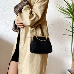 Sac à main élégant en velours noir avec chaîne dorée et fermoir vintage sur un mannequin