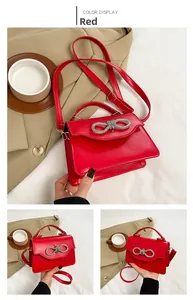Detail of red crossbody bag featuring a large sparkling rhinestone bow and smooth finish