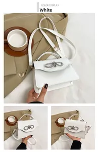 Detail of white PU leather crossbody bag with silver rhinestone bow and gold hardware