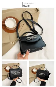 Detail of black crossbody bag with rhinestone bow and matte leather texture in a lifestyle setting