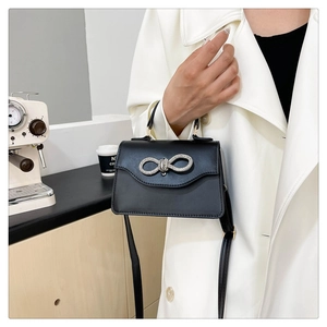 Detail of black leather handbag with sparkling silver bow buckle in a lifestyle setting