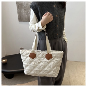 Detailed close-up of quilted tote bag featuring brown flower leather patches and nylon texture