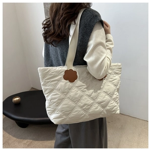 Detail of quilted tote bag with brown flower leather patches on the shoulder strap
