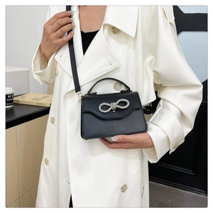 Detail of a chic black crossbody square bag featuring a sparkling silver bow buckle closure
