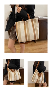 Detail of striped canvas tote bag with brown straps and adjustable shoulder strap