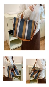 Detail of striped canvas tote bag showing brown leather handles and adjustable shoulder strap
