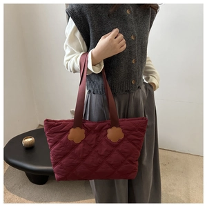 Quilted burgundy tote bag with floral leather accents shown on a model for daily use