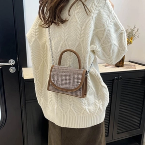 Brown vintage handbag with silver rhinestones and chain strap worn over a white sweater