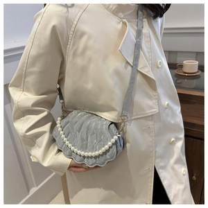 Detail of silver shell-shaped crossbody bag featuring pearl chain and pleated texture