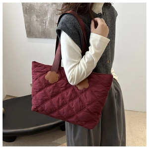 Close-up of wine red quilted tote bag featuring floral strap connectors and diamond stitching