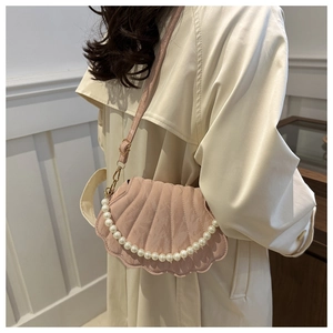 Detailed view of pink shell-shaped quilted bag with pearl handle and fine strap