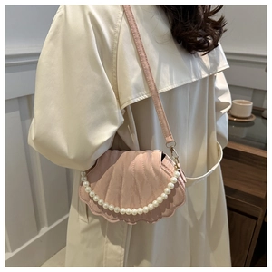 Pink shell handbag with pearl handle and leather strap shown on a beige coat outfit