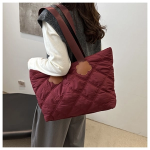 Detailed view of the burgundy quilted tote bag with brown floral leather accents