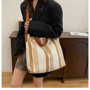 Close-up of yellow and white striped knit tote bag with adjustable brown shoulder straps