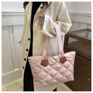 Detail of pink quilted puffer tote bag featuring decorative brown flower patches