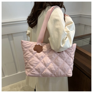 Detail of pink quilted tote bag showing diamond stitching and brown floral leather accents