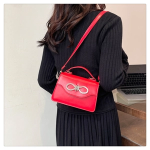 Detail of red leather crossbody bag with sparkling silver rhinestone bow on the front