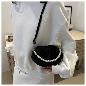 Detail of shell-shaped black crossbody bag with decorative pearl handle and slim strap