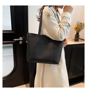 Detail showing fashion embossed leather label on a black matte tote bag for women