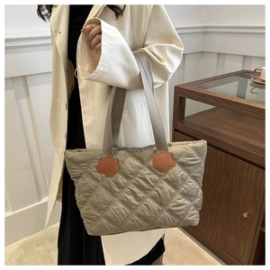 Quilted tote bag detail featuring greyish-green fabric and orange flower charm accents