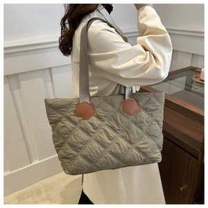 Close-up of quilted diamond pattern and floral leather accents on a khaki shoulder bag