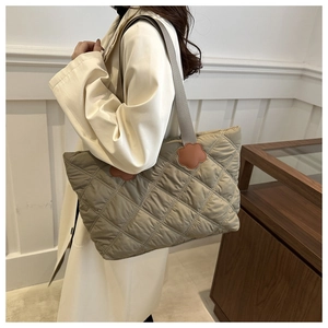 Close-up of quilted olive green tote bag with floral accents worn over the shoulder
