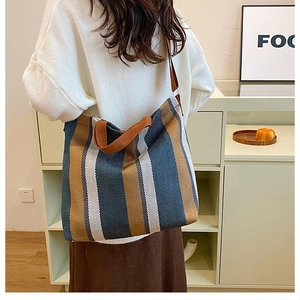 Detailed back view of model wearing a large striped canvas tote bag in blue and brown