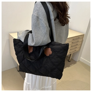 Detail of black quilted tote bag with brown floral patches on model's shoulder