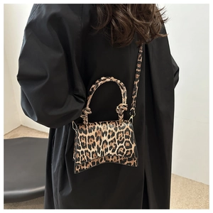 Détail macro du sac à main léopard avec base incurvée distinctive et poignée nouée chic
