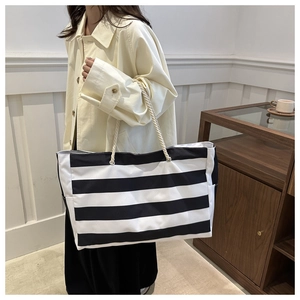 Detail der schwarz-weiß gestreiften Canvas-Tasche mit gewebtem Seilgriff am Modell