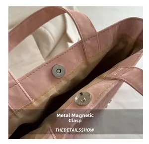Detailopname van de zilveren magnetische gesp op de roze draagtas met stoffen voering