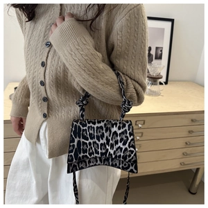 Sac à main léopard tendance avec base incurvée et détail de nœud porté par un mannequin