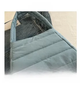 Detail of light blue quilted nylon shoulder bag showing puffy texture and parallel stitching