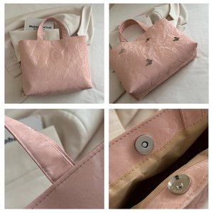 Detail van roze geplooide draagtas met strikbeslag, magneetsluiting en luxe stiksel