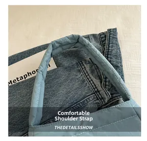 Detail of blue denim shoulder bag showing the wide padded comfortable strap and texture