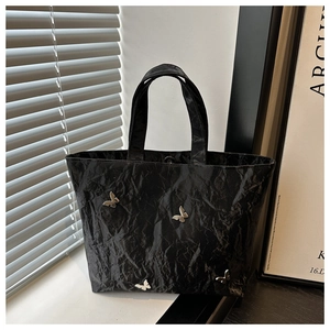 Detail van zwarte geplooide shopper met zilveren vlinders en magnetische sluiting