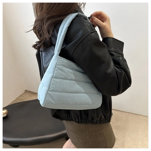 Detail of light blue quilted puffer shoulder bag showing texture and stitching finish