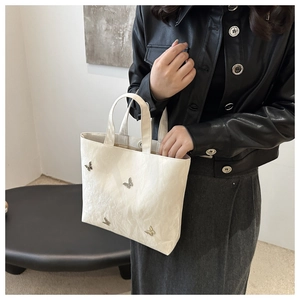 Detail of off-white tote bag featuring metallic butterflies and pleated silk texture