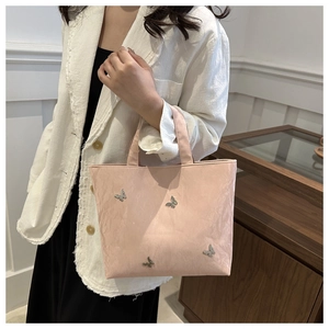 Roze shopper met metalen vlinderdetails gedragen door een model in lifestyle setting