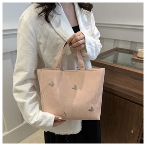 Pink tote bag detail with metallic butterfly ornament and shiny pleated texture finish