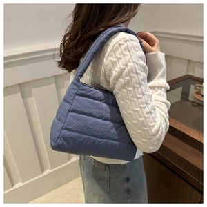 Detail of blue quilted padded shoulder bag showing soft puffer texture and stitching