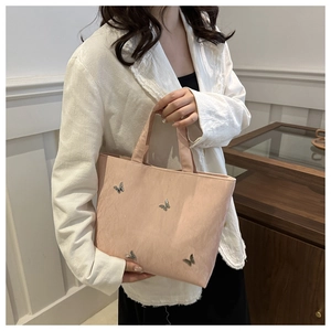 Detail of a large pink tote bag featuring metal bow buckles and soft faux leather texture