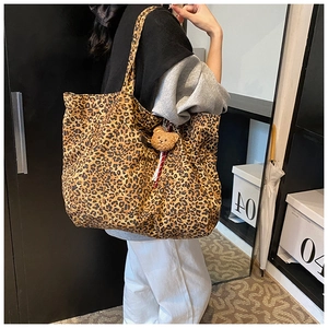 Detail of leopard print canvas tote bag featuring a cute plush bear charm accessory