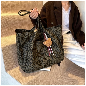 Detailed view of the large leopard print canvas tote bag with a cute bear charm pendant