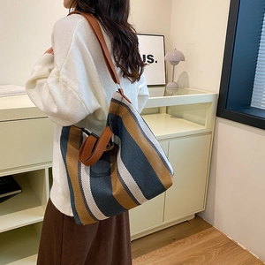 Détails de la texture tricotée d'un grand sac cabas rayé avec des lanières en cuir marron
