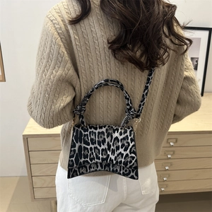 Sac bandoulière léopard avec poignée nouée présenté dans un cadre de vie intérieur chaud