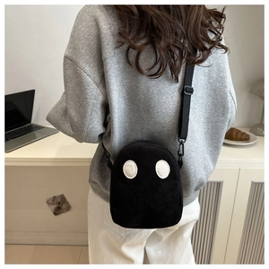Détail du sac bandoulière fantôme en velours côtelé noir porté par le mannequin en situation